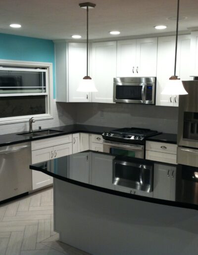 A kitchen with a black counter top and stainless steel appliances.